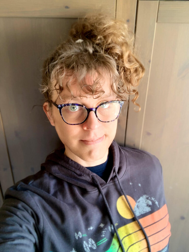 ME with my hair up in a pineapple, in a black hoodie with a kind of rainbow, 80s-styled Star Wars print on it