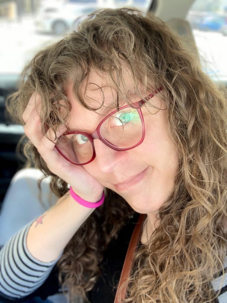 Me in the driver’s seat of our car, holding my head in one hand, my hair is a super mess from the wind.