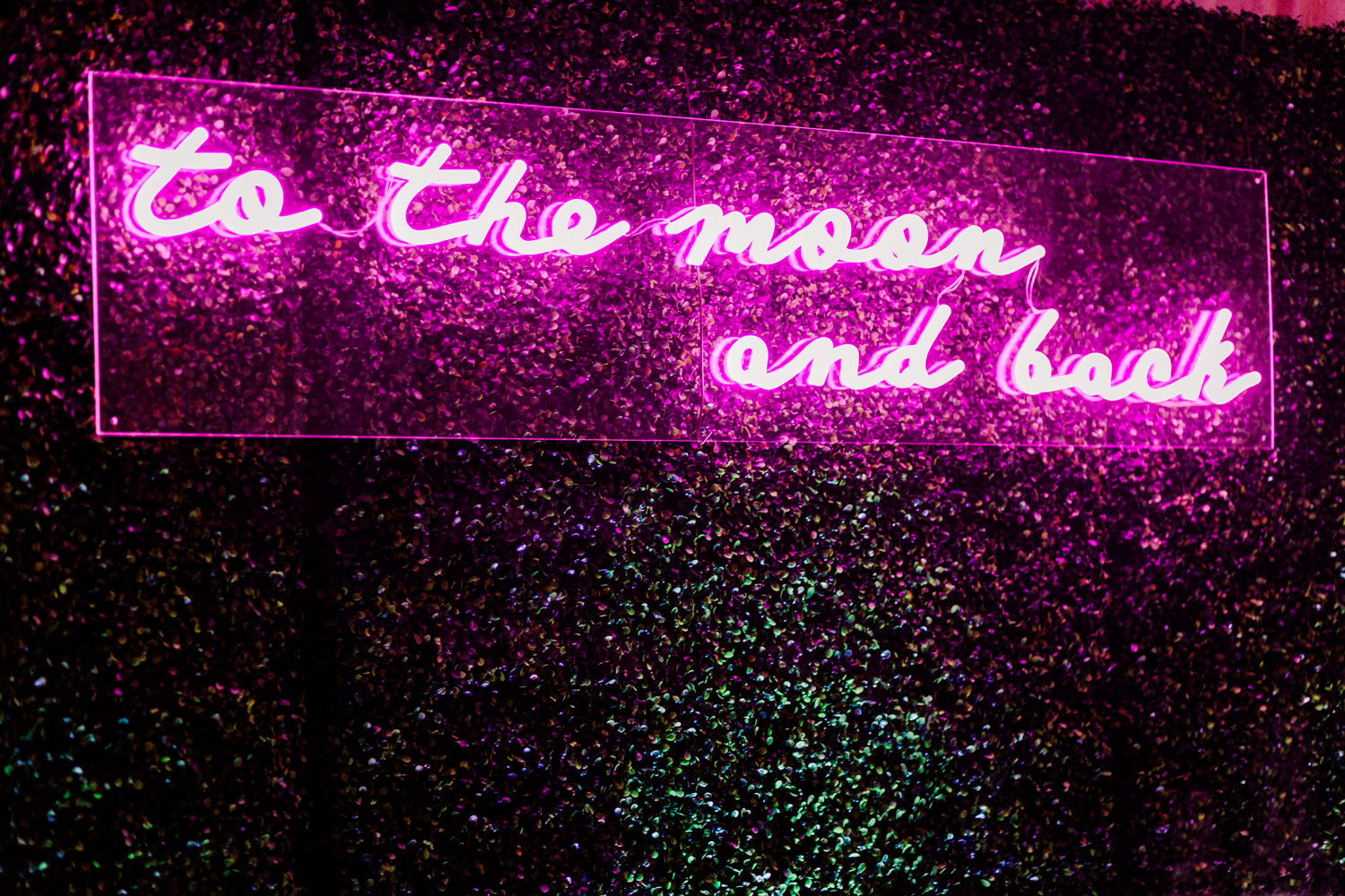 a neon sign that says “to the moon and back” in a bright pink fuchsia