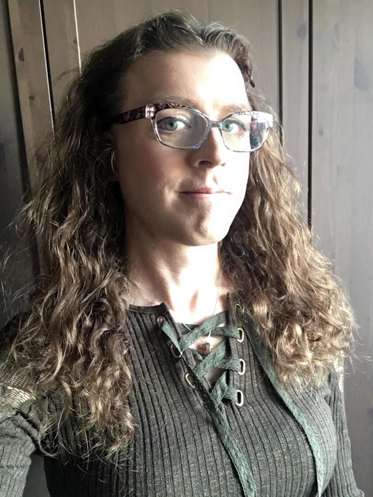 Me with long curly brown hair, in a green top that laces up near the neckline