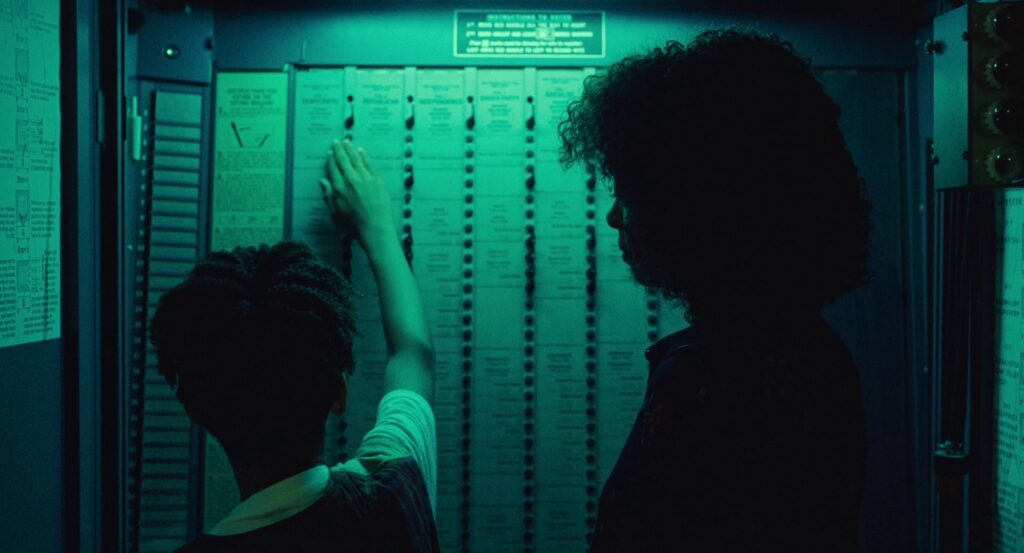 Owen runs his hands over the buttons on the voting card, a blue-green light shining down from above.