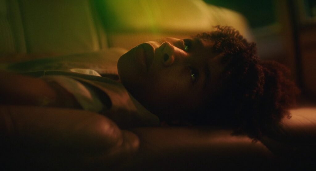 Owen lying on the back seat of a car, as yellow, red, and green lights wash over him.