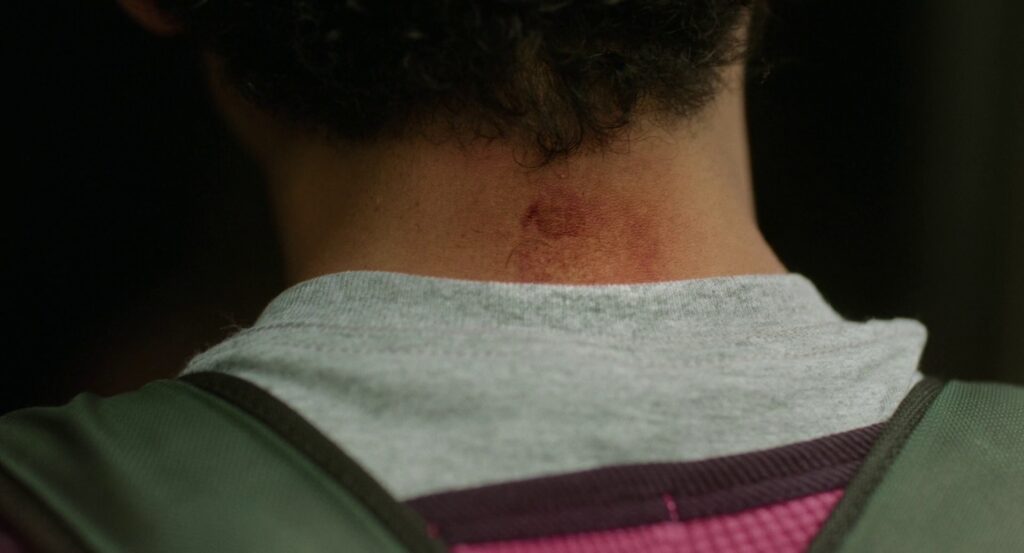 The back of Owen’s neck, showing faint hints of pink from where he scrubbed off Maddie’s drawing. He still wears his pink shirt, but now it’s under GREEN.