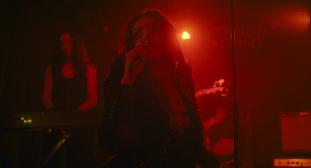 A woman singing on stage bathed in entirely red light.