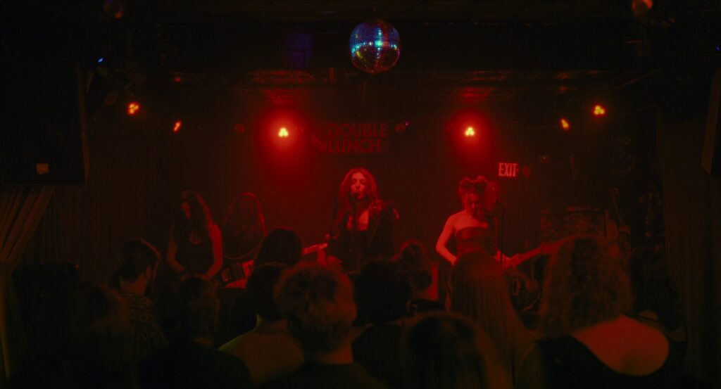 The song continues, still bathed in red, but now we can see the sign on the back wall reads “Double Lunch.”