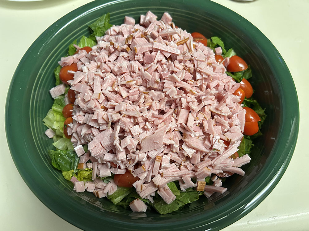 a mega sized green bowl full of lettuce, chopped grape tomatoes, and about a pound of diced deli turkey